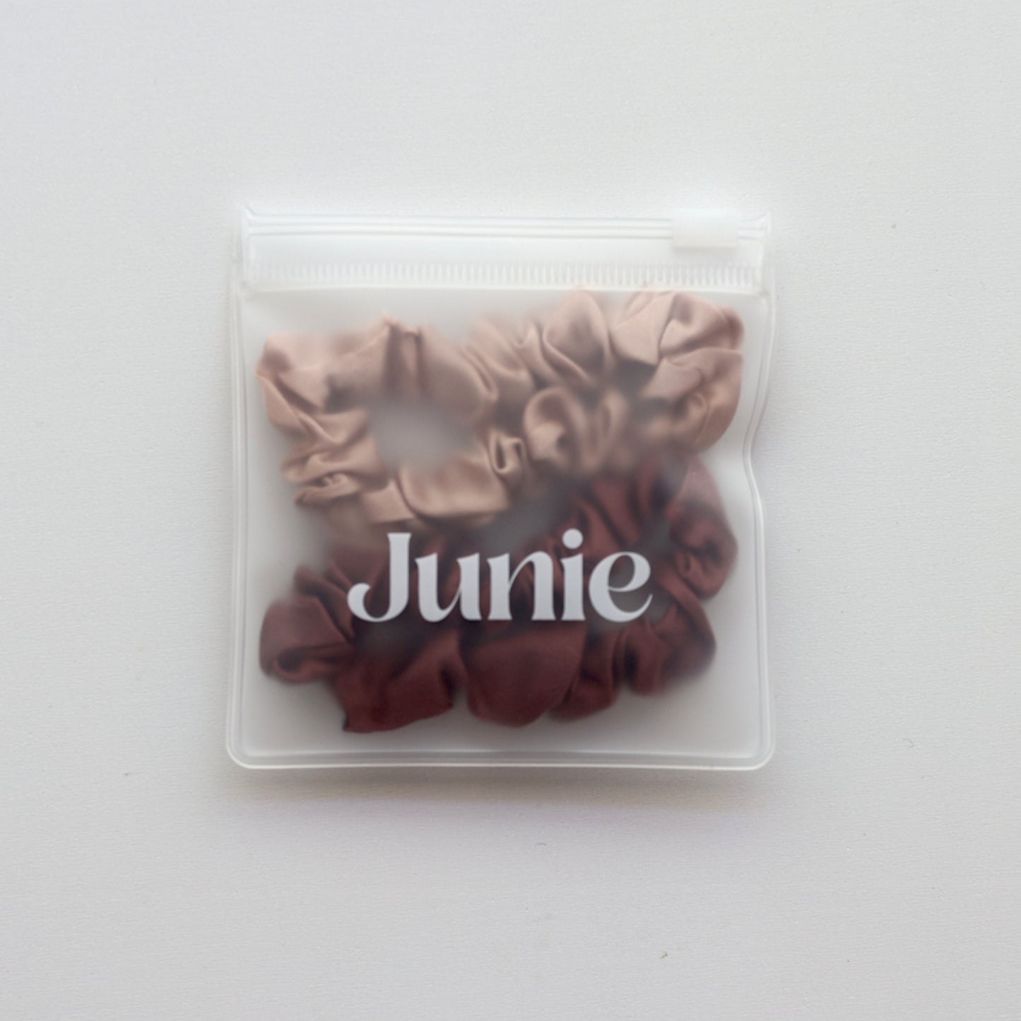 Two brown scrunchies in a clear plastic bag with 'Junie' branding on a white background
Junie silk hair scrunchies in two colours, in a reusable zip lock bag