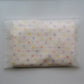 A folded cream-colored Junie quick dry kids hair towel with multicolored polka dots, sealed inside a clear plastic bag with printed instructions on the front.