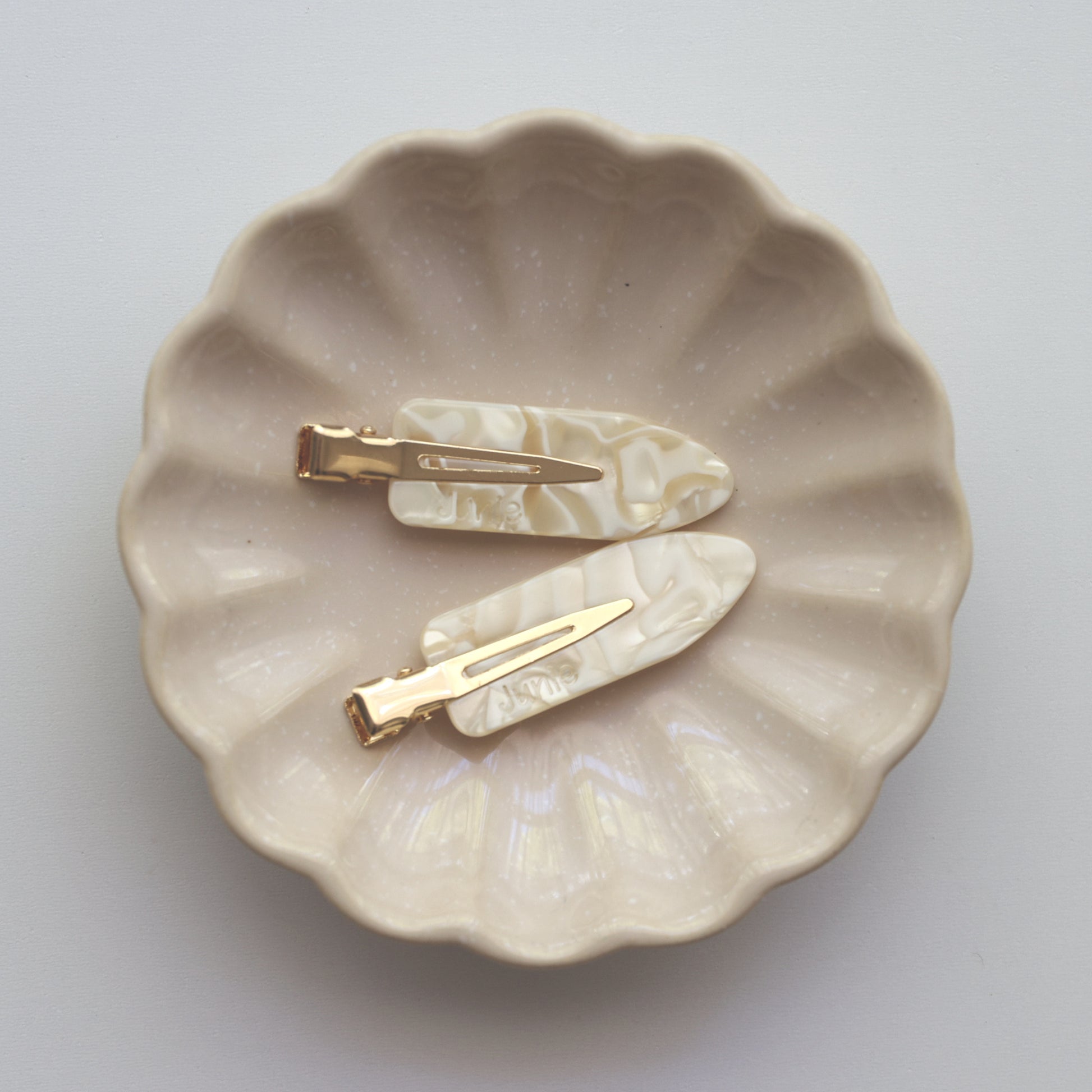 Two Junie hair clips on a scalloped ceramic dish, gentle hold during styling
