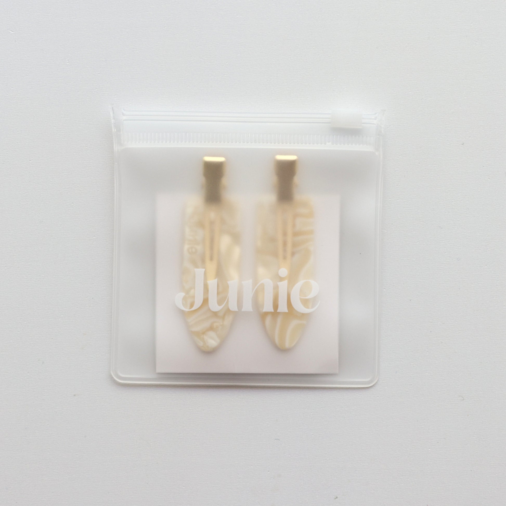 Junie crease-free hair clips in ivory with gold accents, neatly packaged in a reusable zip lock bag with Junie branding for gifting or storage
