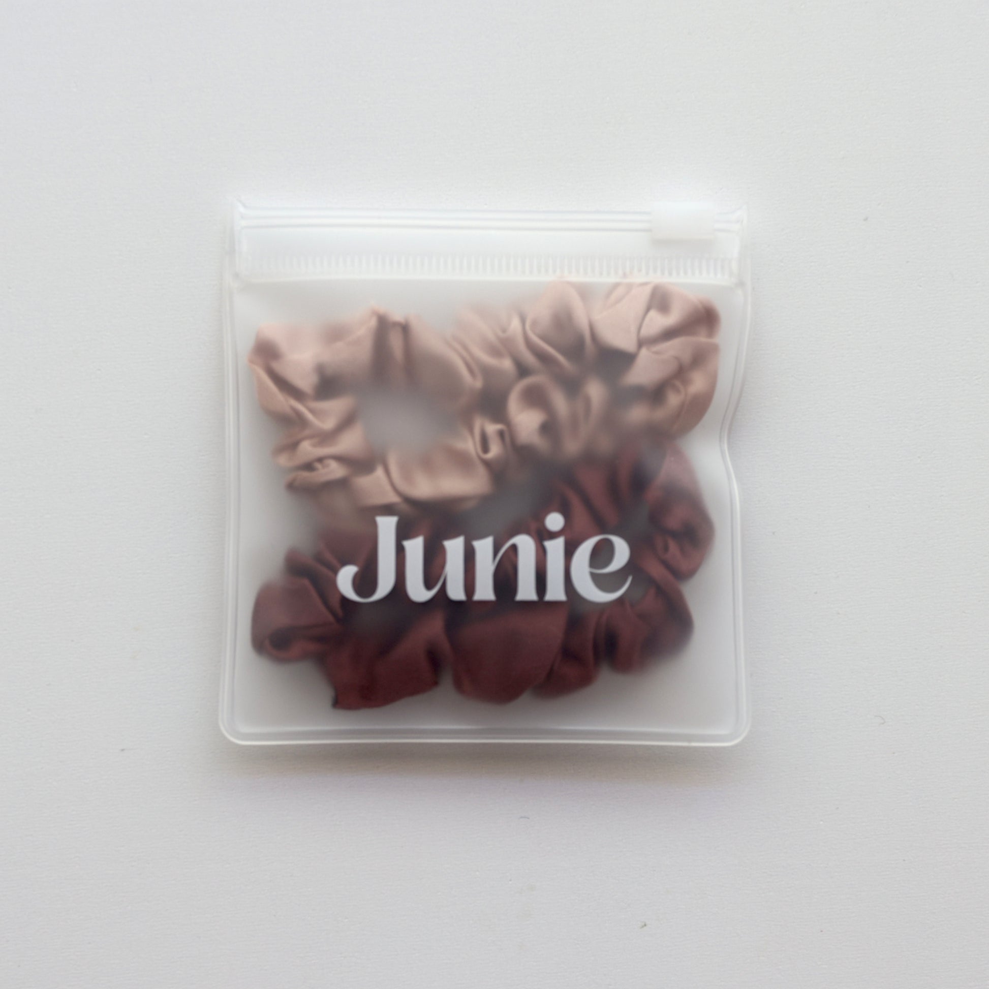 Two brown scrunchies in a clear plastic bag with 'Junie' branding on a white background
Junie silk hair scrunchies in two colours, in a reusable zip lock bag
