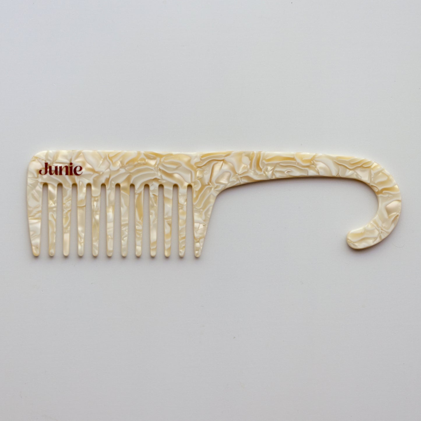 Junie wide-tooth comb in ivory, designed to gently detangle wet or dry hair. Decorative comb with 'Junie' branding on a white background. 