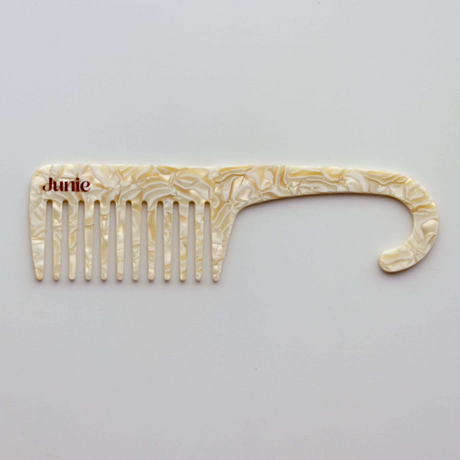Junie wide-tooth comb in ivory, designed to gently detangle wet or dry hair. Decorative comb with 'Junie' branding on a white background. 